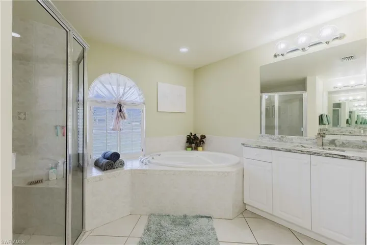 Full bathroom featuring vanity, tile patterned flooring, a garden tub, and a shower stall