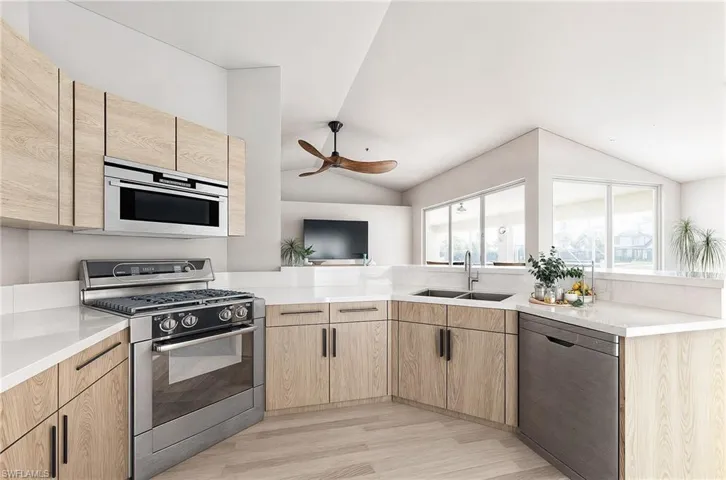 VIRTUAL REMODEL/STAGING: Kitchen featuring light brown cabinets, stainless steel appliances, vaulted ceiling, and light wood-type flooring