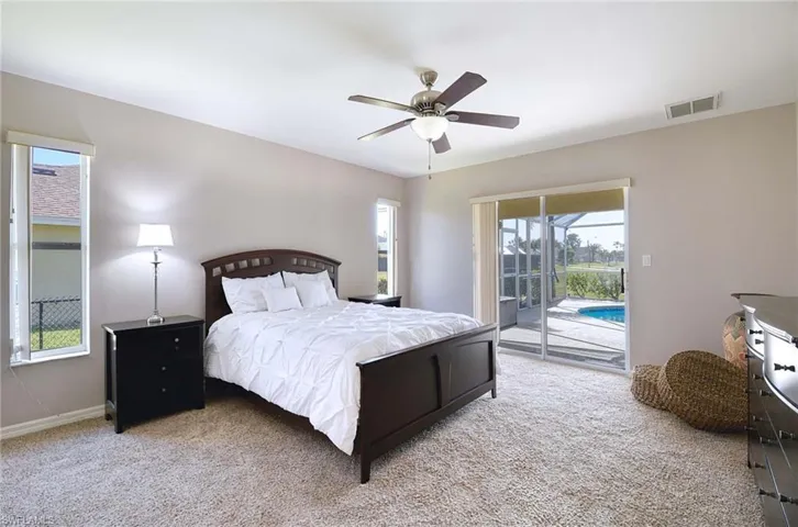 Primary Bedroom with access to outside pool area, ceiling fan, light colored carpet and queen bed