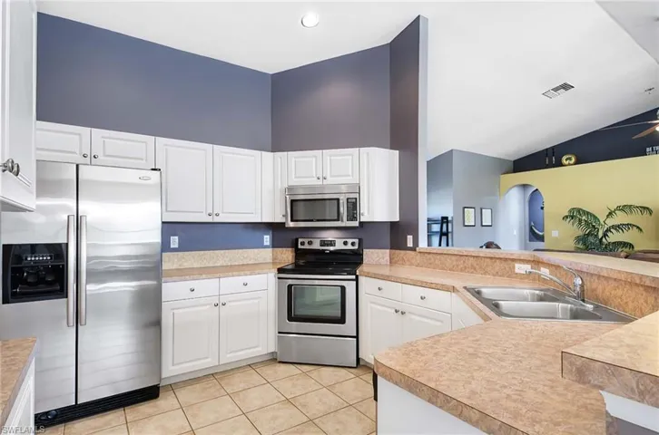 Kitchen with light tile patterned flooring, sink, kitchen peninsula, and stainless steel appliances