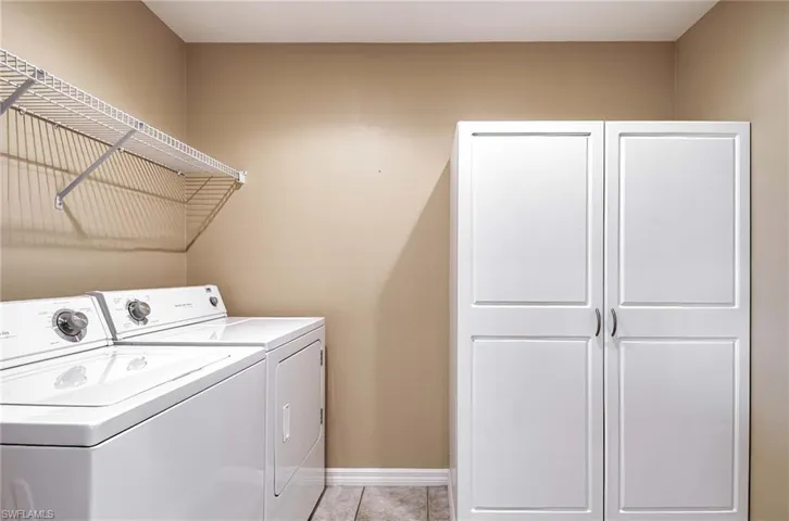 Laundry area with cabinets, washing machine and dryer, and light tile patterned flooring