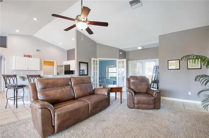 Living room featuring ceiling fan, light tile patterned floors, high vaulted ceiling, and french doors