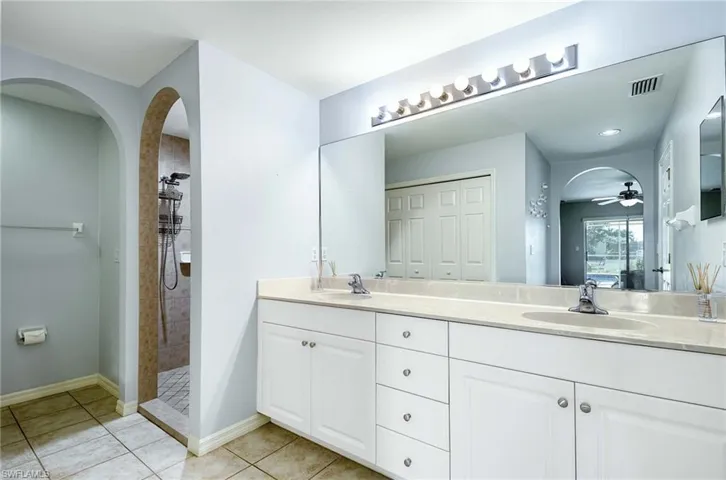 Primary Bathroom en-suite with a tile shower, double vanity, ceiling fan, and tile patterned floors