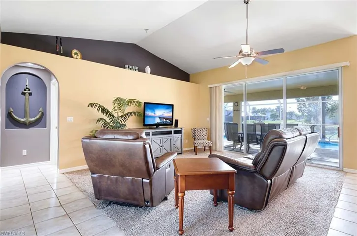 Tiled living room with ceiling fan and lofted ceiling