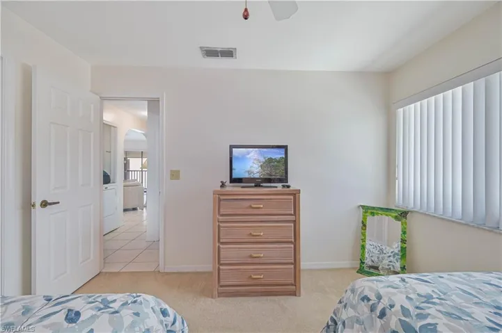 Carpeted room featuring a ceiling fan, a window with vertical blinds, a solid core door, and a light-colored wall finish
