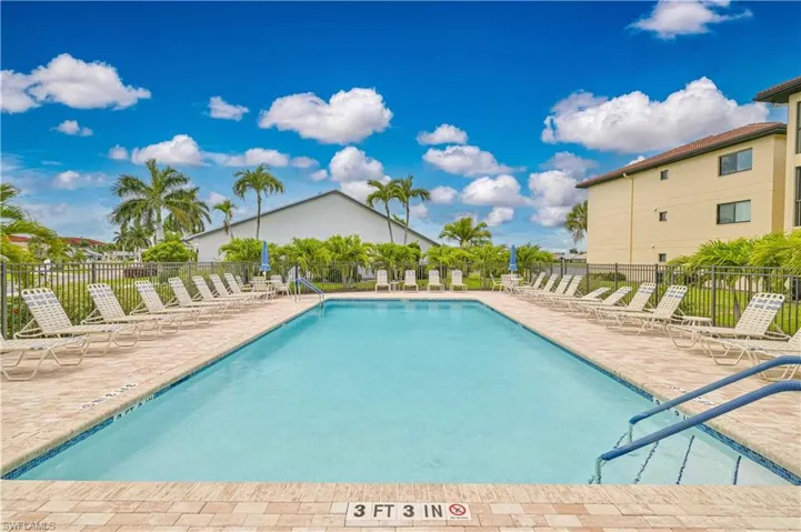 Rectangular outdoor swimming pool featuring a brick paver surround and blue waterline tiling
