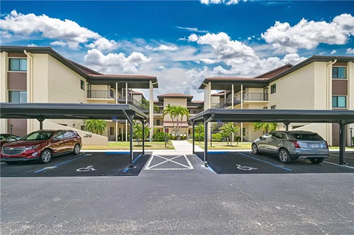 Building exterior featuring stucco finish, multiple private balconies with black railings, covered walkways, and a tile roof