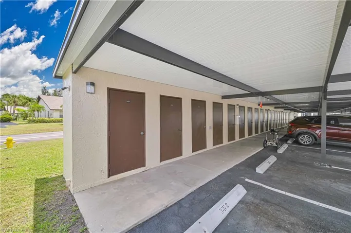 Covered parking structure featuring multiple storage units with individual brown doors and exterior lighting fixtures
