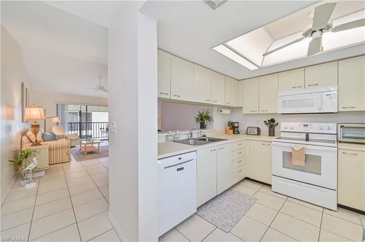 Kitchen featuring light-toned cabinetry, white appliances, and a recessed ceiling light panel