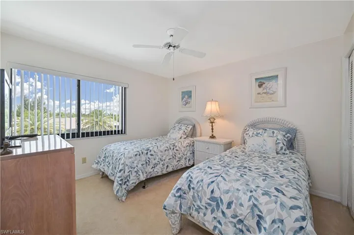 Room featuring a wide window with vertical blinds, a ceiling fan, and light-toned carpet flooring