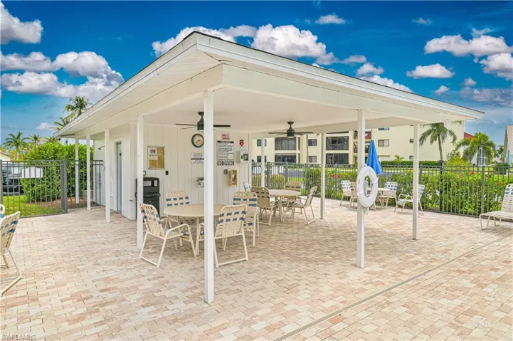 Covered outdoor patio area featuring a paver surface, ceiling fans, and multiple tables