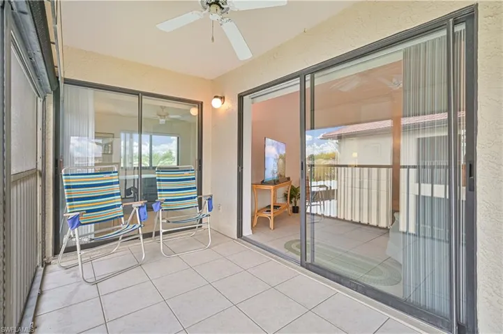 Screened balcony with light-toned square tile flooring, ceiling fan, and recessed lighting
