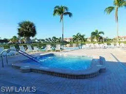 Swimming pool featuring an integrated spa, surrounded by a paver deck and lounge seating