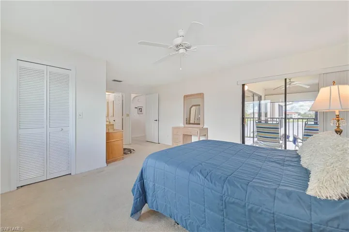 Bedroom featuring carpeted flooring, a ceiling fan, louvered closet doors, and direct access to a private balcony through sliding glass doors