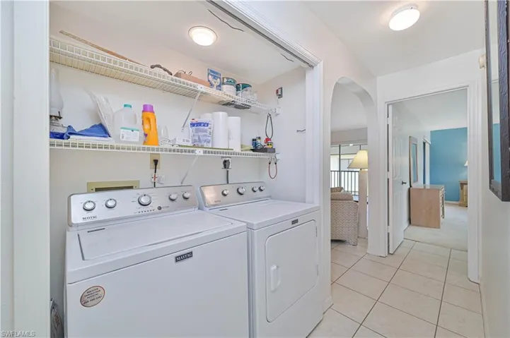 Dedicated laundry area featuring a white washer and dryer pair, integrated wire shelving, and overhead flush-mount lighting