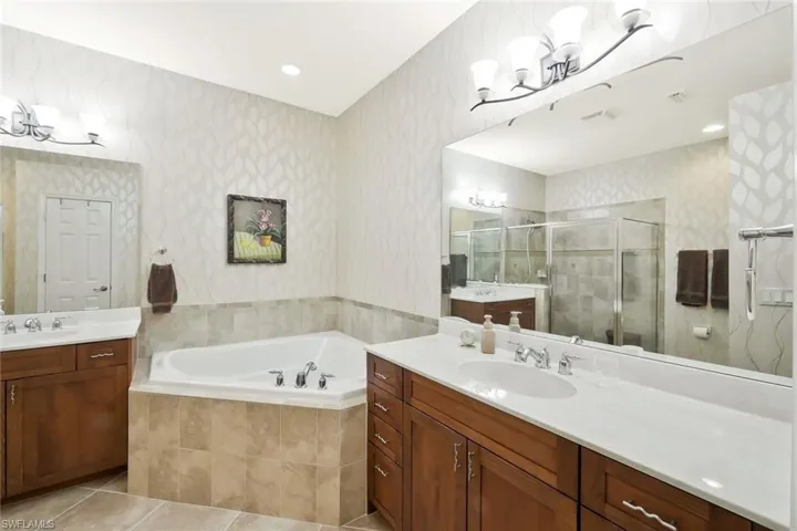 Bathroom with a sink, a stall shower, a notable chandelier, and wallpapered walls