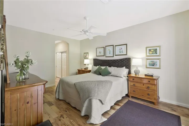 Bedroom featuring arched walkways, baseboards, light wood-style flooring, and a closet