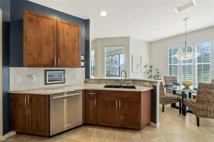 Kitchen featuring decorative backsplash, a peninsula, a sink, light stone counters, and stainless steel dishwasher