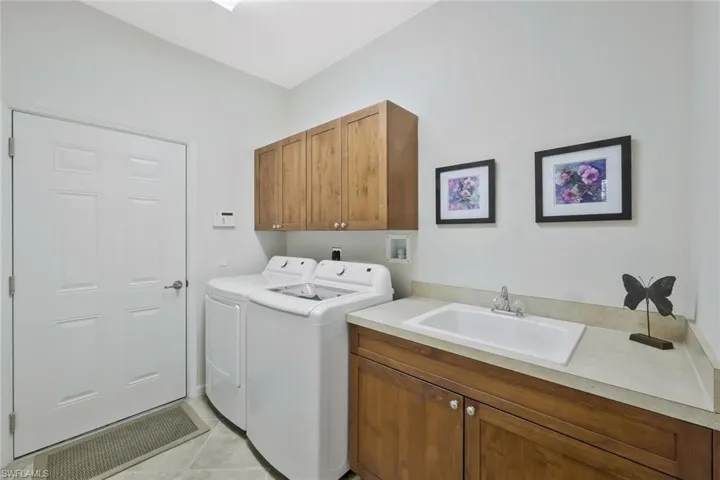 Washroom featuring independent washer and dryer, a sink, cabinet space, and light tile patterned flooring