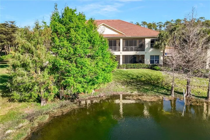 Rear view of property featuring a tiled roof, a sunroom, a water view, and stucco siding