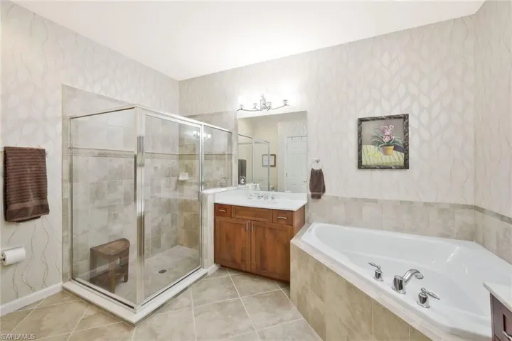 Bathroom featuring a stall shower, wallpapered walls, vanity, and a garden tub
