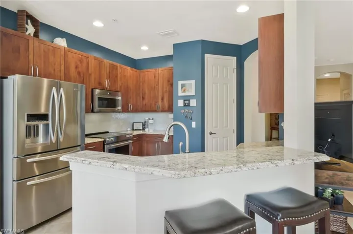Kitchen featuring light stone countertops, a sink, and appliances with stainless steel finishes