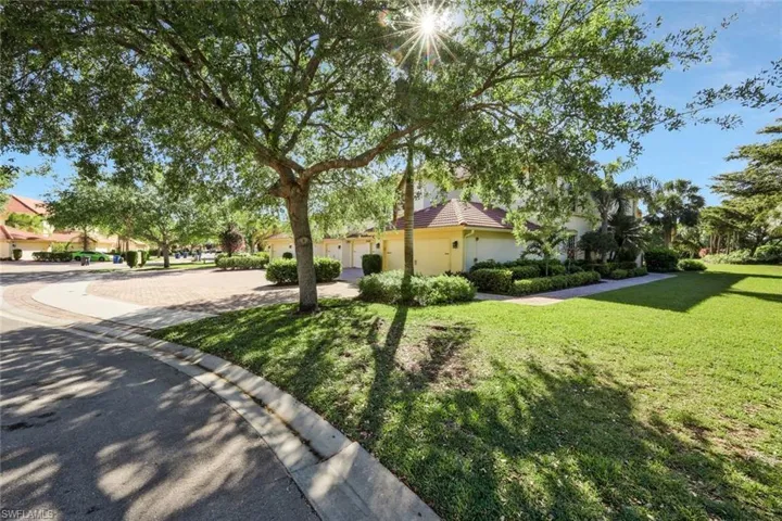 View of side of home with stucco siding, a garage, a tiled roof, and a yard