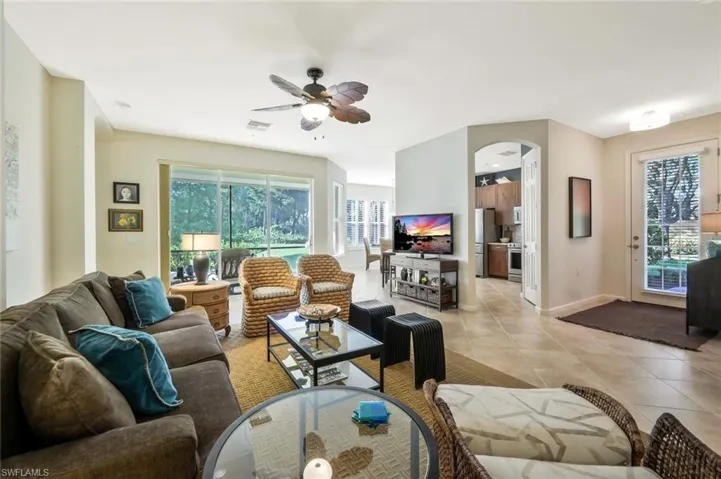 Living room with light tile patterned flooring, visible vents, baseboards, ceiling fan, and arched walkways