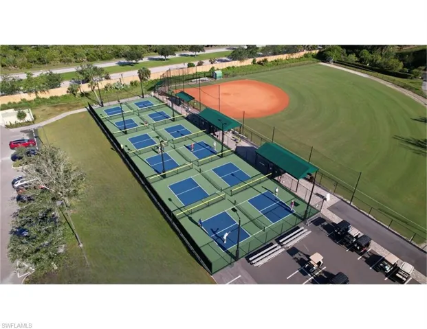 Expansive recreational area featuring multiple pickleball courts with perimeter fencing, shaded spectator areas, and dedicated court lighting