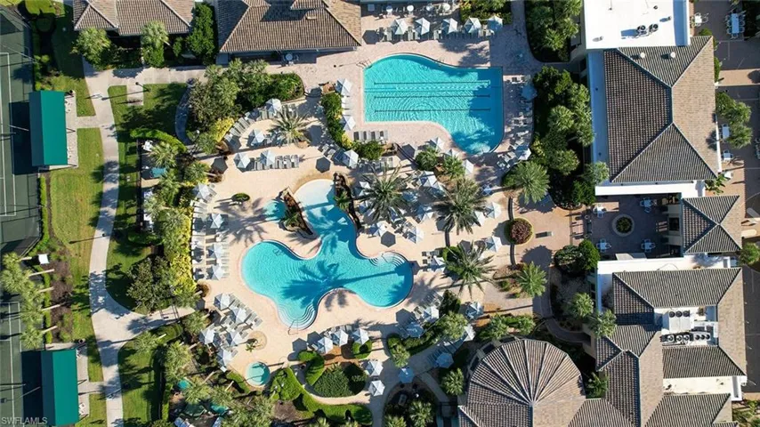 Expansive outdoor amenity area featuring multiple swimming pools, extensive patio decking, mature palm trees, and lush landscaping