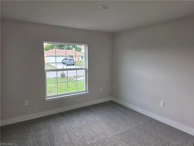 Carpeted room featuring a single window, white baseboards, and a recessed ceiling light
