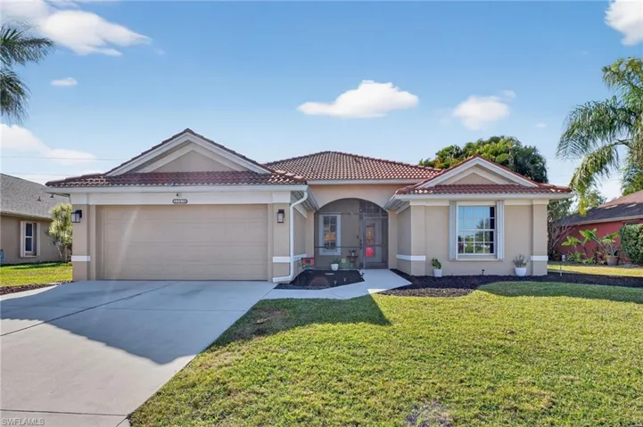 Mediterranean / spanish house featuring a tiled roof, stucco siding, driveway, an attached garage, and a front lawn
