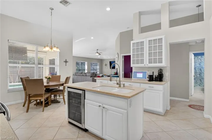 Kitchen featuring glass fronted cabinets, white cabinets, open floor plan, a ceiling fan, and a high ceiling