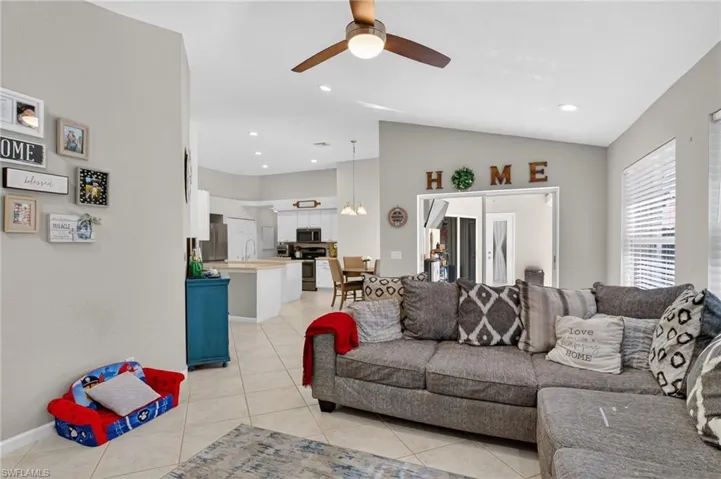 Living room with a ceiling fan, vaulted ceiling, light tile patterned flooring, and recessed lighting