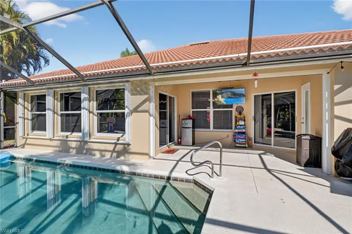 Back of property featuring a sunroom, a patio, an outdoor pool, and glass enclosure