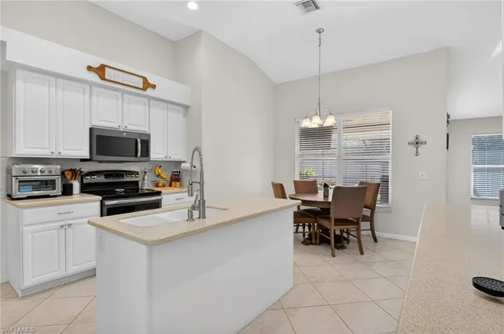 Kitchen with white cabinetry, stainless steel appliances, light tile patterned flooring, and lofted ceiling