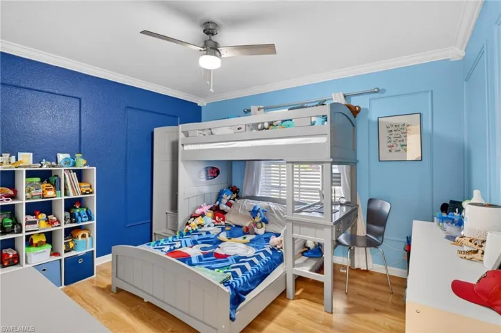 Bedroom with light wood-type flooring, ornamental molding, and a ceiling fan