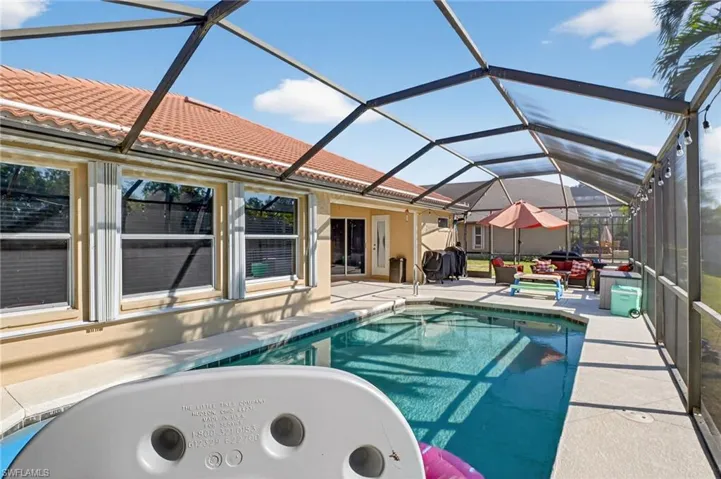 Swimming pool featuring a sunroom, a patio area, and glass enclosure