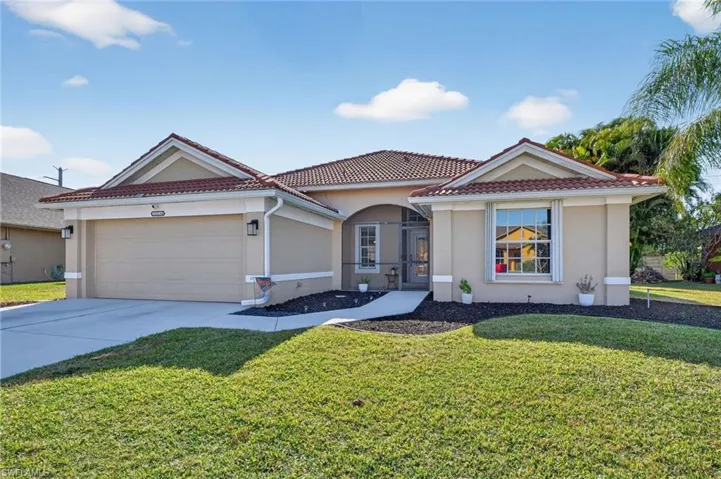 View of front of property featuring stucco siding, concrete driveway, a tile roof, and a front lawn