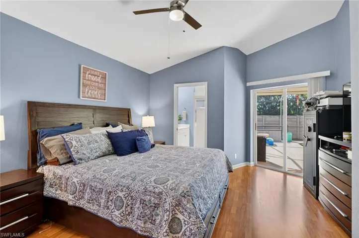 Bedroom with access to outside, light wood-style flooring, vaulted ceiling, ceiling fan, and ensuite bathroom