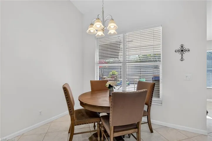 Dining area with hanging lights, light tile patterned flooring, and lofted ceiling