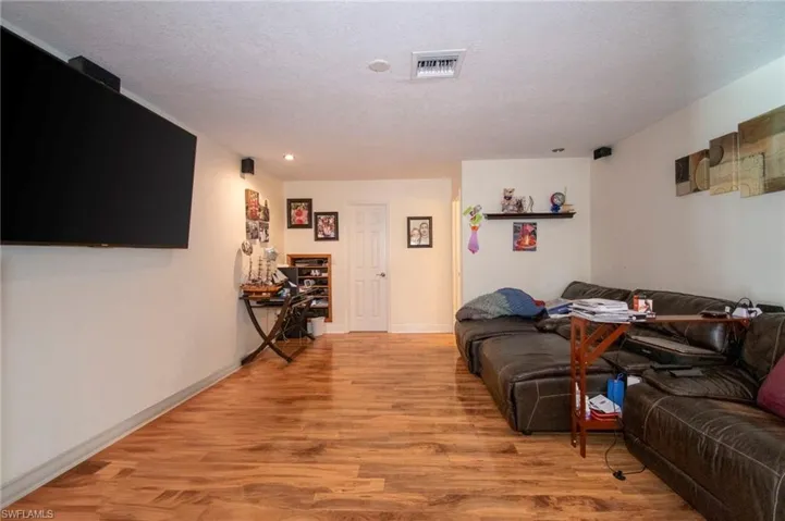 Living area with recessed lighting, visible vents, light wood-type flooring, baseboards, and a textured ceiling