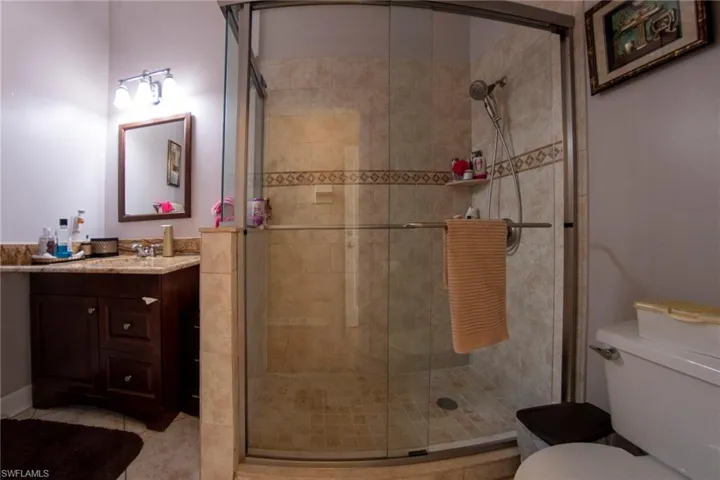 Bathroom with a stall shower, vanity, tile patterned flooring, and toilet