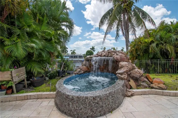 View of pool with an outdoor hot tub and fence
