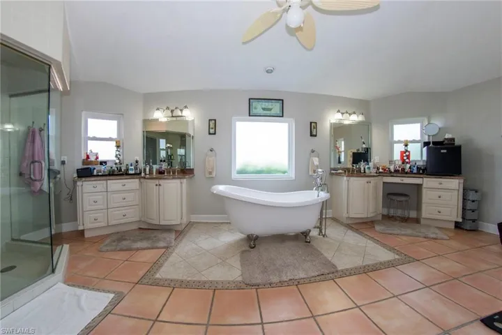 Full bath with a shower stall, a freestanding tub, tile patterned flooring, and a ceiling fan