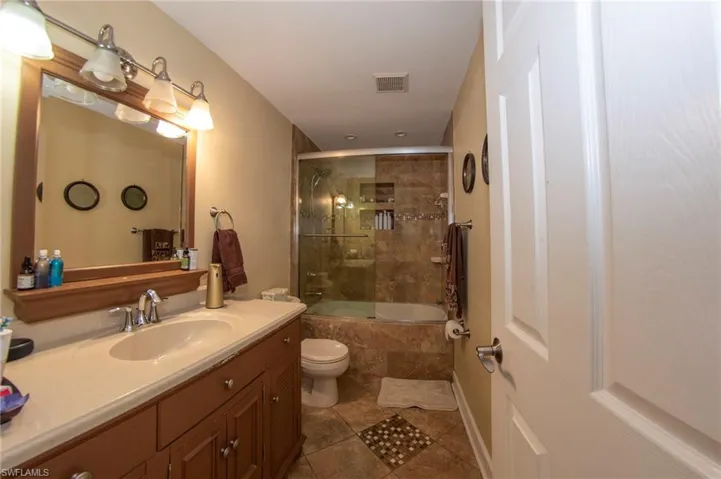 Full bath with tiled shower / bath, vanity, toilet, tile patterned flooring, and visible vents