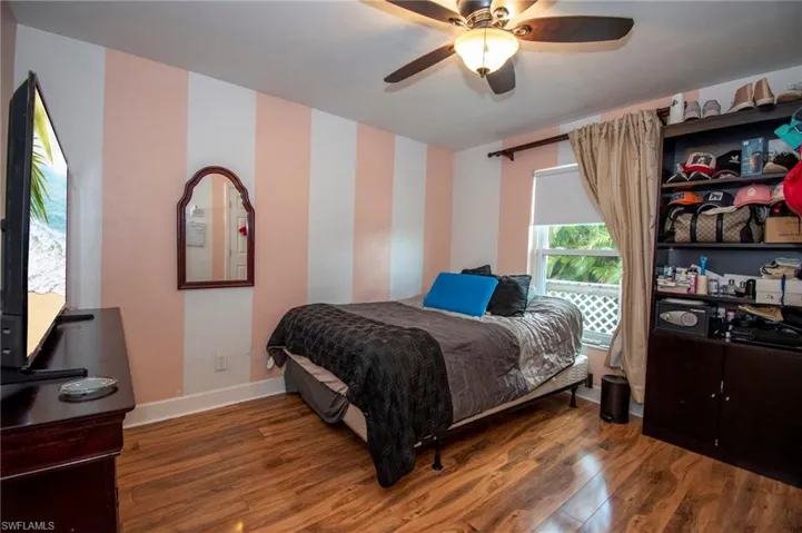 Bedroom featuring baseboards, wood finished floors, and ceiling fan