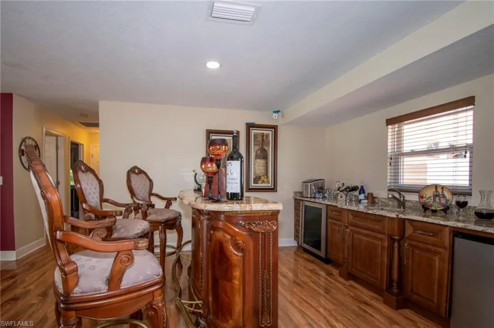 Kitchen with dark wood finished floors, baseboards, visible vents, and wine cooler