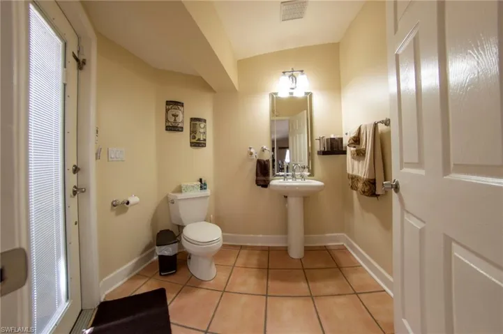 Bathroom featuring toilet, tile patterned floors, visible vents, and baseboards