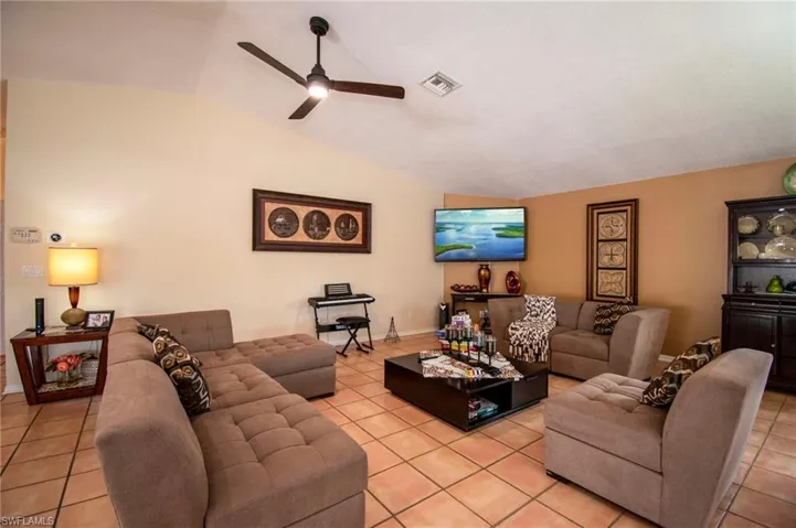 Living area featuring lofted ceiling, visible vents, ceiling fan, and light tile patterned floors